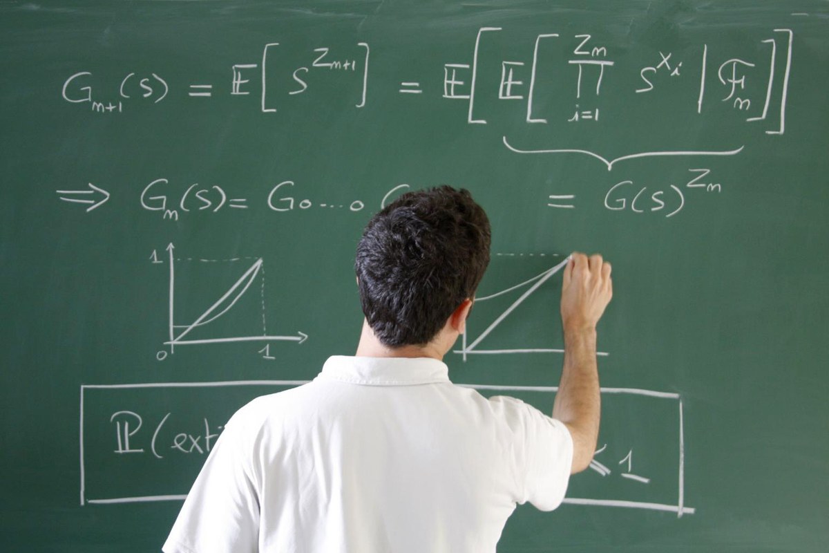 Matematikas rašo lygtis ant žalios lentos