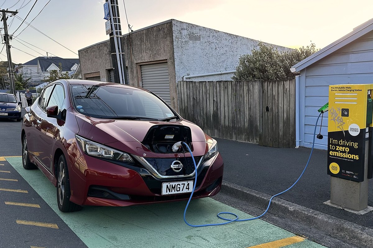 Raudonas Nissan Leaf įkrovimo stotelėje