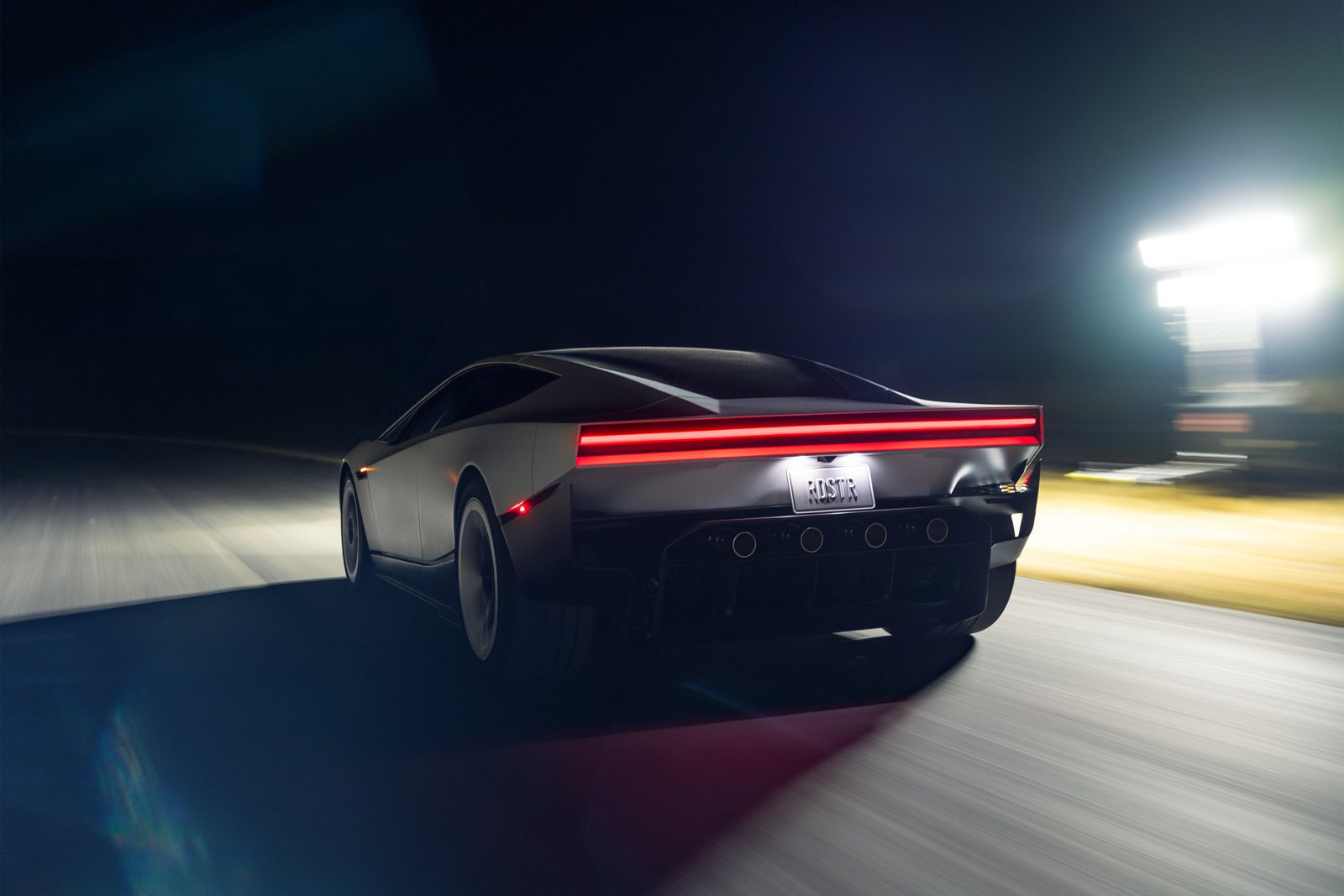 „Tesla Roadster“ važiuoja naktį, matyti galiniai žibintai